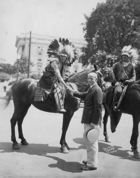 Mayor Albert G. Schmedeman greeting Chief Shunatuna, who is on horseback and who is in Madison with the Official United States Indian band at the RKO Orpheum theater. The band played at the inauguration of President Hoover.