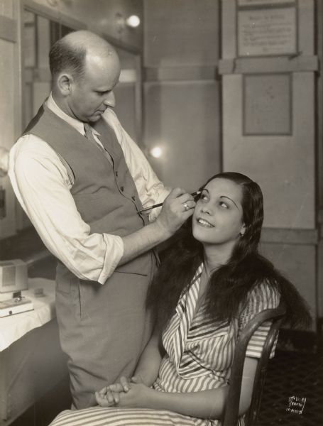 Reri (Anne Chevalier), Tahitian star of the Fanchon and Marco "Tahiti" show at the Orpheum theater, having her eyebrows penciled in her dressing room by Mr. Sinykin from Cinderella cosmetics.