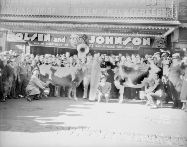 Ole Olson and Chic Johnson milking cows in front of the Orpheum, 216 State Street, promoting their show "Atrocities of 1932" at the Orpheum.