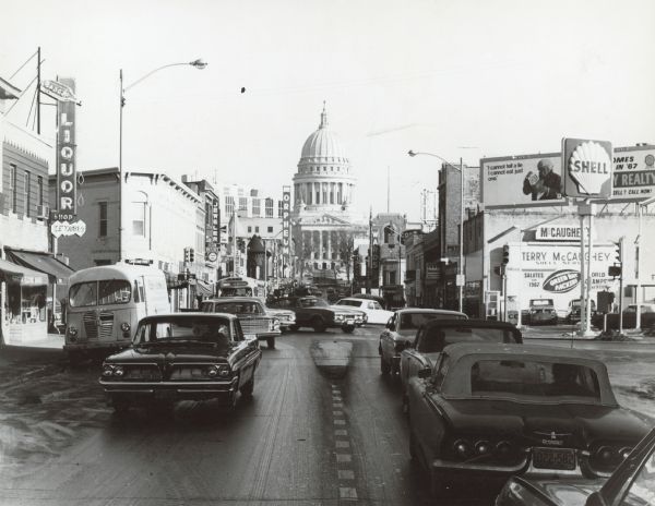 View down center of State Street towards the intersection of W. Gorham Street. On the near left corner is the Badger Liquor Shop. On the right on the other side of Gorham is Terry's Shell gas station (Terry McCaughey).