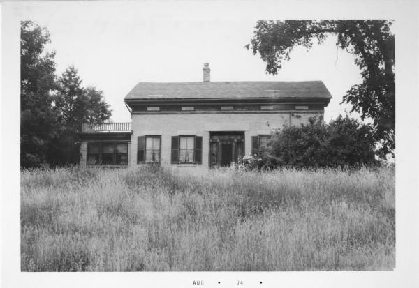 Exterior view of the William Noyes House, with tall grass in the foreground.