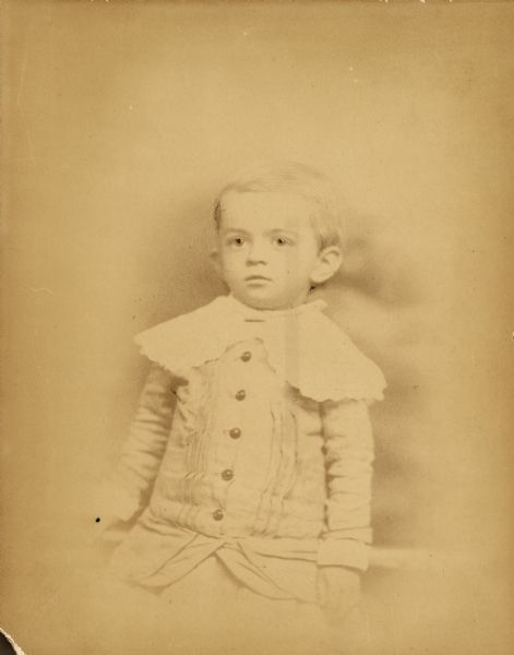 Portrait of Ed Sullivan when he was two or three years old.  He is wearing a coat with a large collar, and five big buttons and pleats down the front. 