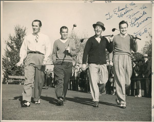 Ed Sullivan, Bing Crosby, Bob Hope and an unidentified man are smiling and walking on a golf course. Spectators are stand behind a rope in back of the foursome.  Each man is carrying a driver. The handwritten inscription reads: "To Edward the/Hacker/From the/Lakeside/Terror/Bob." 