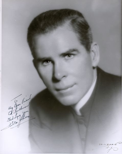 Head and shoulders portrait of Bishop Fulton J. Sheen. He is looking directly at the camera and is wearing a priestly frock coat and white clerical collar. The handwritten inscription reads: "To/My Dear Friend/Ed Sullivan/God Love You/Fulton J. Sheen."