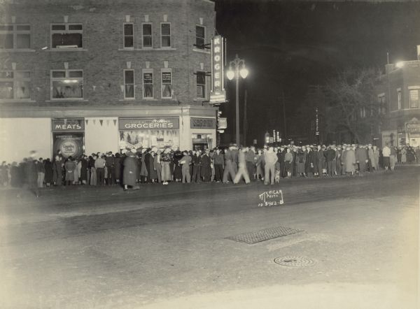 Night scene across street towards a crowd in front of the new Kroger grocery store at the corner of State, Johnson and Henry, (looking towards Johnson Street) at 245 State Street. Savidusky's Cleaners is at 301 State Street.