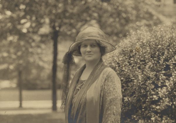 Outdoor portrait of Belle Case La Follette wearing a hat. Text on back of print reads: "In the garden of their house on 16th St. in Washington near Comm Ave."