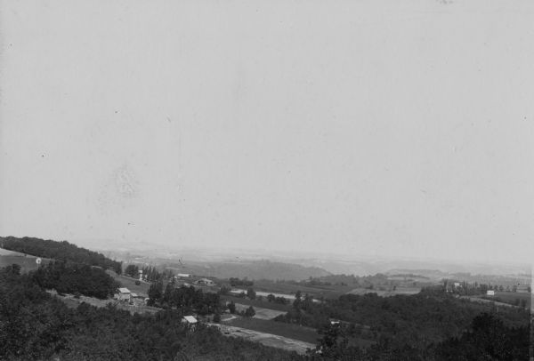 Elevated view along hillsides towards several buildings, forests, and part of a river. Caption reads: "View from N.W. 1/4 of N.W. of Sec. 31. L. 12. R 6 W, looking N.W. toward Victory and mouth of Bad Ax River."