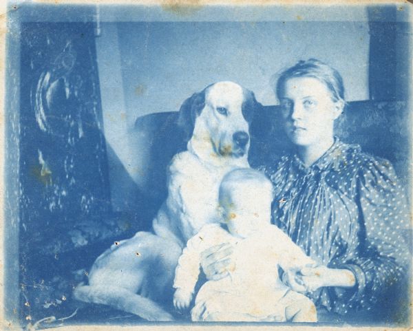 Group portrait of a young woman and an infant, and a large dog named Barry sitting on a couch.