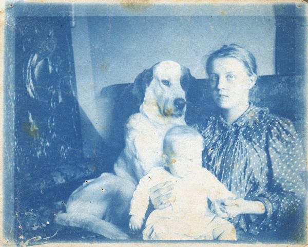 Group portrait of a young woman and an infant, and a large dog named Barry sitting on a couch. The infant is probably Sigrid Schultz and the woman is probably her mother Hedwig.