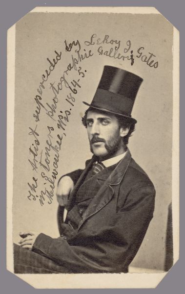 Carte-de-visite portrait of a man wearing a suit and a top hat sitting sideways in a chair. Written on print: "The Artist superceded by LeRoy J. Gates in Stoners photographic Gallery, Milwaukee, Wis. 1864-65."