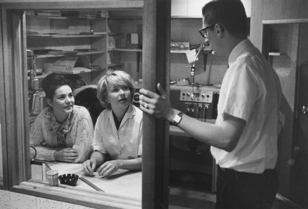 Caption reads: "Young Disc Jockeys, Mary Speth and Peggy Schaefer, get briefing from announcer, Del Viney. Station strictly limits rock-'n-roll to one hour a day, makes teens responsible for scheduling, announcing."