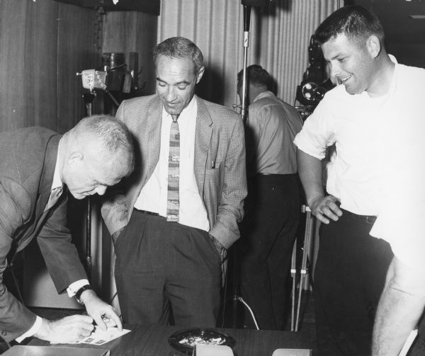 James Kitchell, standing on right, with two men next to him: John Glenn Jr. on the left, and unknown person in the center.