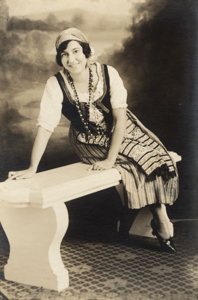 Opera singer, Olivia Monona in costume posing on a bench.