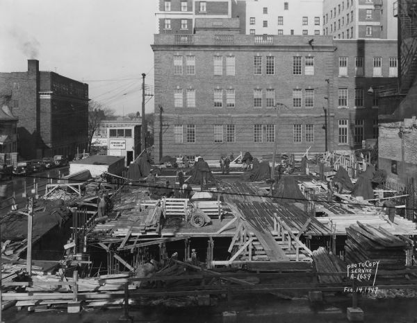 Elevated view of the Wisconsin Telephone Co. building site, 122 West Main Street, looking north across basement and first floor. Also shows side views of YMCA, 207 West Washington Avenue and telephone building, 17 South Fairchild Street. Building constructed by J.H. Findorff & Son Inc. construction company.