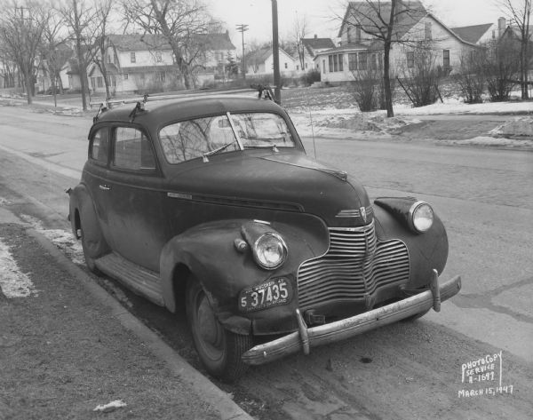 Chevrolet car, Mr. Kurth owner, showing front and right side with damage to fender, parked at the curb. Across the street are houses at 407, 413, and 417 North Street.