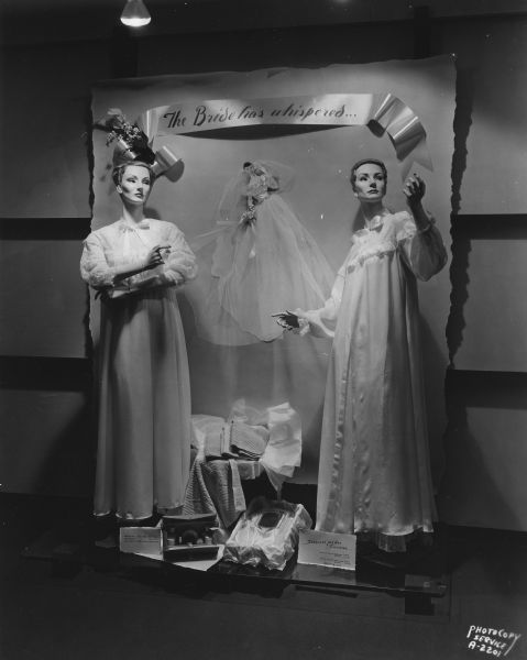 "The Bride Has Whispered" foyer display at Manchester's, Inc., 2 East Mifflin Street, featuring a sign that reads: "treasures for the trousseau," and two mannequins wearing negligees.
