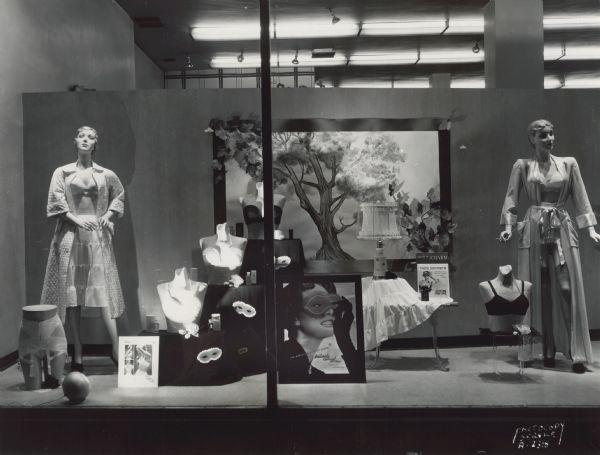 "Tres Secrete" inflatable bra and lingerie display in Manchester's, Inc., window display with two mannequins. A sign in the center of the window reads: "Intimate Apparel 2nd Floor."