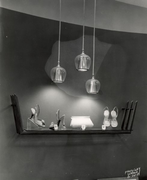 Interior of Chandler's Shoes store, 10 West Mifflin Street, on the Square, featuring a wall display shelf with shoes and a handbag, and three hanging ceiling lights.