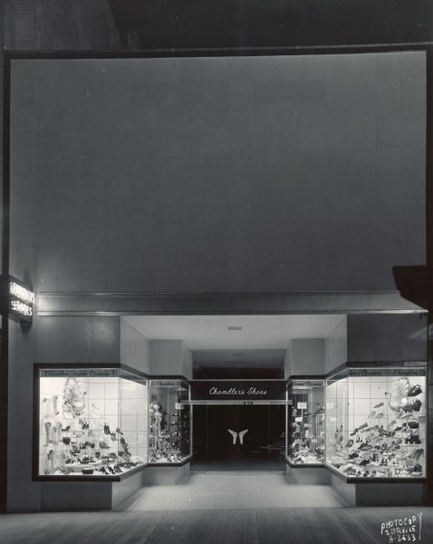 Night view of Chandler's Shoes store, 10 West Mifflin Street, on the Square, showing entrance and Grand Opening display windows featuring shoes and handbags.