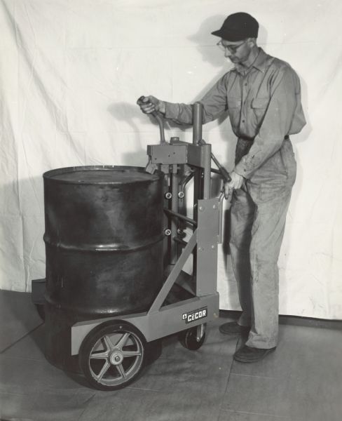A man is clamping a barrel onto a hydraulic barrel lifter at the Coolant Equipment Corporation.