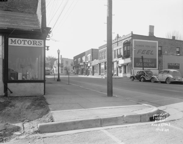 East Wilson Street at corner of South Hancock intersection looking toward West Wilson Street-King Street intersection taken to document site of Reynolds Bus accident scene. Business seen at near corner is Electric Motor Service at 323 East Wilson Street. Business seen at far corner is Schroeder & Son Funeral Service, 235 King Street. Businesses seen along north side of East Wilson Street include the Shell Service at 324 East Wilson Street, Young's Cafe at 316 East Wilson Street, Madison Watch Shop at 314 East Wilson Street, Volunteers of America at 310-12 East Wilson Street, Fred Kessenich (United Autographic Register Company) at 308 East Wilson Street, Johnson Maytag Company at 306 East Wilson Street, Meyer Printing at 304 East Wilson Street, and Stop Lite Tavern, 302 East Wilson Street.
