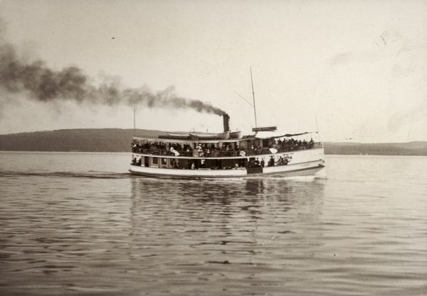 View across water towards the "Plowboy" ferrying passengers across the lake. The far shoreline is in the distance.