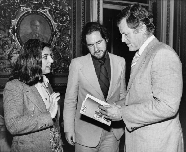 From left to right are Isabel Letelier, Michael Moffett, and Ted Kennedy. Kennedy is holding a book.