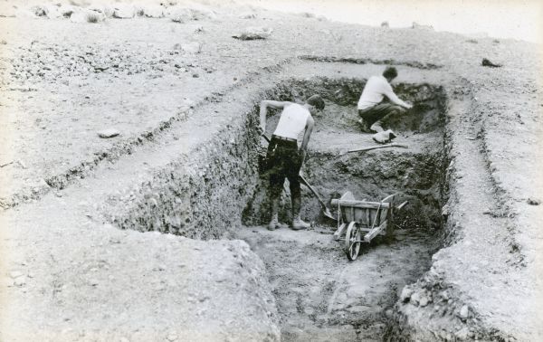Two men, Riedel and Krieger, working in a trench on an archaeological dig.