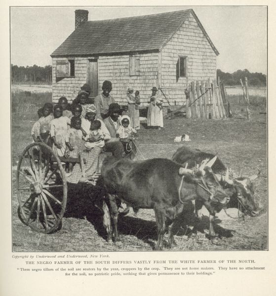 A Southern African American family posing outdoors in front of their house. The children are in an oxcart in the foreground, and the parents are behind them, each holding a child in their arms. Caption reads: "The negro farmer of the south differs vastly from the white farmer of the north. 'There negro tillers of the soil are renters by the year, croppers by the crop. They are not home makers. They have no attachment for the soil, no patriotic pride, nothing that gives permanence to their holdings.'"