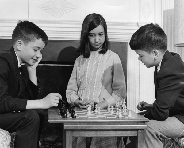 The children of Wisconsin Governor, Pat Lucey. From left to right: Paul, Laurie, and David Lucey. Paul and David are playing chess while Laurie is watching.