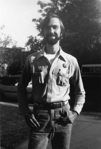 A man is standing and posing outdoors. He is wearing a small pin that reads "Stop the Bombing in El Salvador CISPES." Caption reads: "Martin Wolke, organizer from Chicago."