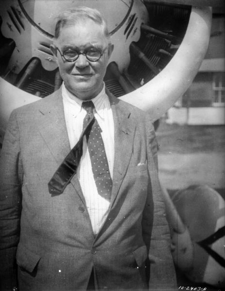 Outdoor portrait of a man, likely William J. Newman, standing in front of the prop of an airplane.