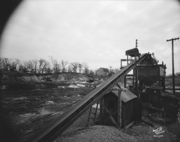 Wisconsin Foundry & Machine Co. conveyor belt loading gravel into hopper which is filling a C.E. & P.A. Roth truck at their gravel pit, 1910 Roth Street near North Sherman Avenue. There is a barn and a steam shovel in the background.