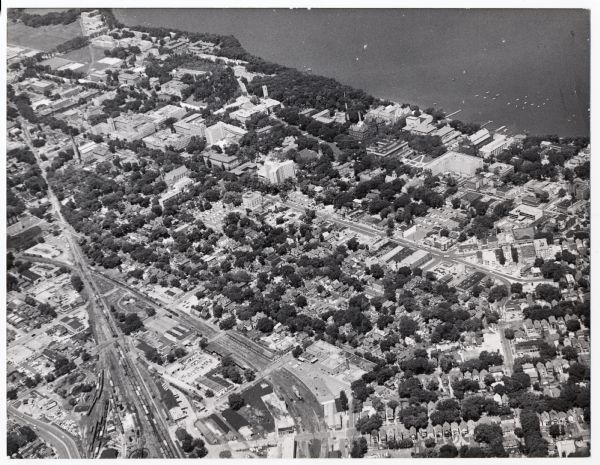 Aerial view looking northwest showing an area to be redeveloped into high-rise dormitories. Lake Mendota and Bascom Woods can be seen at the top. University Avenue run parallel to the lake near center. Railroad tracks run from bottom to top at left. 388 structures at center were razed to make way for the South East Dorms.
