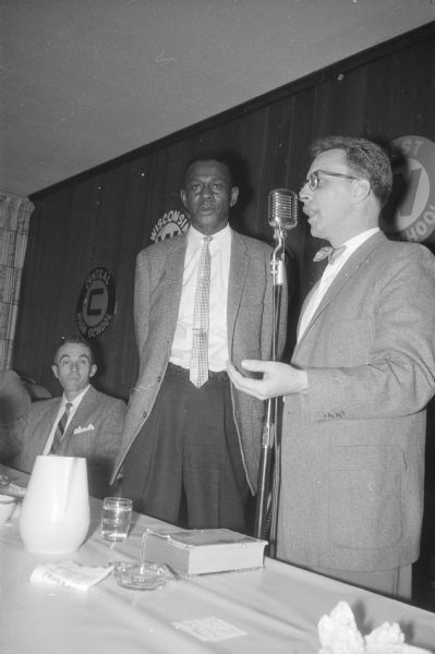 Satchel Paige at the annual high school basketball banquet sponsored by the West Side Business Men's Association, at the WSBM clubhouse. Jim Atkins, president of the WSBM, is standing at the microphone on the right.