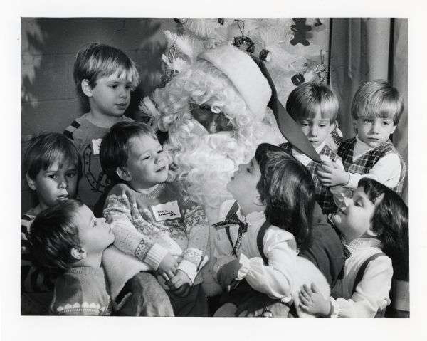 Santa Claus talks with a group of twin siblings at a Christmas party at Mt. Zion Evangelical Lutheran Church. The children in the left background are Joe and Jonathan Jagman and in the right foreground are Scott and Marc Krubsack. On the right are Matthew and Marc Nienas and Amy and Kerri Warzyn.