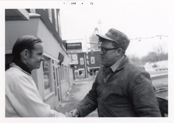 Wisconsin Senator William Proxmire shaking the hand of a man on the street of a Wisconsin town.