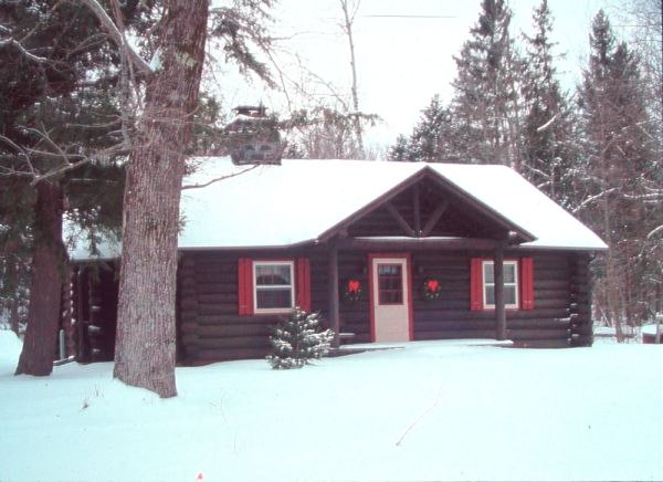 Exterior view of the custodian's residence at Copper Falls State Park in winter. There are evergreen wreaths with red bows on each side of the door.