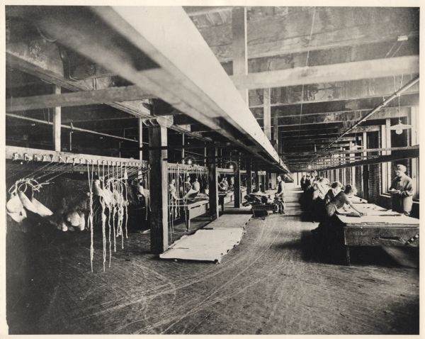 Women working in the N.R. Allen Sons tannery during World War I. The women are finishing leather. An older man is hauling a cart load of hides at center.