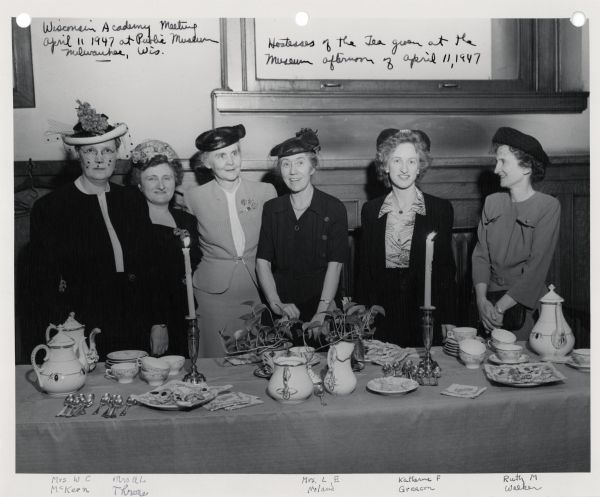 A group portrait of the hostesses of the tea at a Wisconsin Academy meeting. From left to right are Mrs. W.C. McKern, Mrs. Al Throke (sp.), unidentified, Mrs. L.E. Morland, Katherine F. Greacon, and Ruth M. Walker.