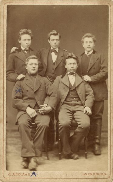 Cabinet card with a studio group portrait of five youth. A blue pen mark is on Soren J. Uhrenholdt who is sitting in the front row on the left. Handwritten caption at bottom reads: "S.J.U. at Danish High School." Borup, Denmark.