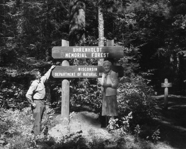 Johanne Uhrenholdt Johnson, daughter of S.J. and Christine Uhrenholdt, and Frank Shafrik, Forester, are standing with a sign to the Uhrenholdt Memorial Forest, Wisconsin Department of Natural Resources.