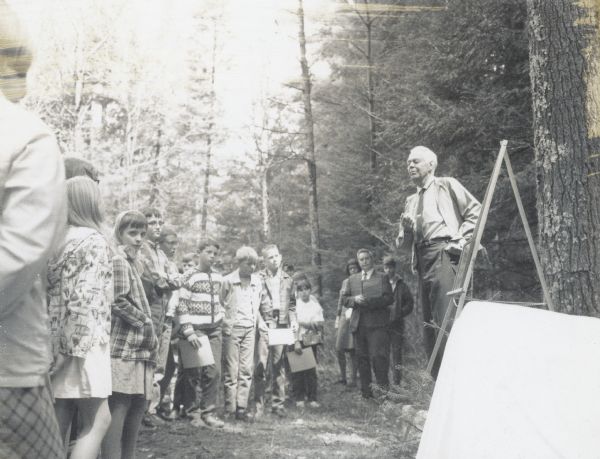 Sigurd F. Olson standing outdoors speaking to a group of people. Sigurd was a son-in-law of Soren and Christine Uhrenholdt.