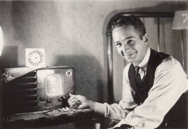 A man is sitting and adjusting a radio.