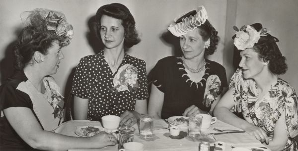 Four women sitting together. Caption from <i>The Capital Times</i>: "Shown above are members of the social planning committee of the Marquette school Mothers' club which arranged the social details of the city-wide Mothers' club dinner held at the Pilgrim Congregational church here Tuesday. They are, left to right, Mrs. Larry Pagel, Mrs. John Haakenson, Mrs. Ben Bergor, and Mrs. Harold Barth."