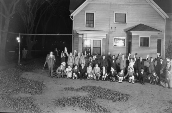 Elevated informal group portrait of students posing outdoors at a Halloween Party, some in costumes, taken outside behind the Presbyterian Student Headquarters building, 731 State Street.