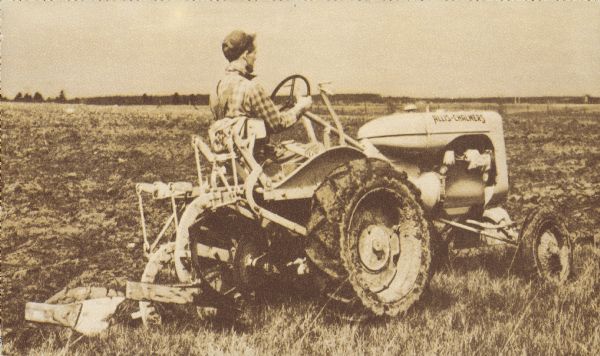 Three-quarter right rear side view of a man driving a tractor. Caption reads: "First choice on thousands of family-operated farms is the Allis-Chalmers MODEL "B" TRACTOR with its matched line of pick-up plows, mowers, single-row planters, cultivators, and fertilizer attachments. See your Allis-Chalmers dealer, or write Allis-Chalmers, Milwaukee, Wisconsin."
