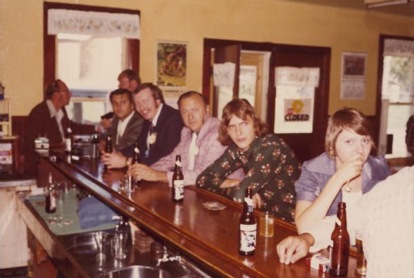 Group of people sitting at the bar. Left to right are: Jim Wittnebel (Tom's brother), John Rawlins (brother-in-law), Ron Kliest (brother-in-law), Dick Wittnebel (cousin), Frank Unertl (Penny's father), Mark Unertl (Penny's brother) and Linda Gerring (Penny's sister). Tom is Roy and Lorraine's son.
