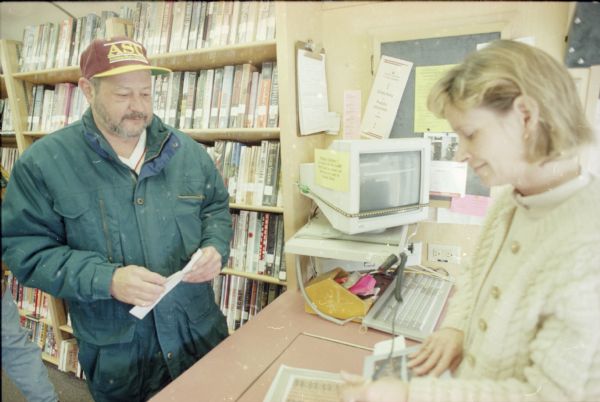 Cathy Surprise (Chambers) assists a male patron (possibly Rod Clark) in the Dane County Library Service Bookmobile.