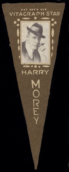 Brown felt pennant featuring a photograph of silent film actor Harry Morey. The small photograph shows Morey wearing a hat and holding a cigar in his hand which is near his face. He is also identified as a Vitagraph Star.